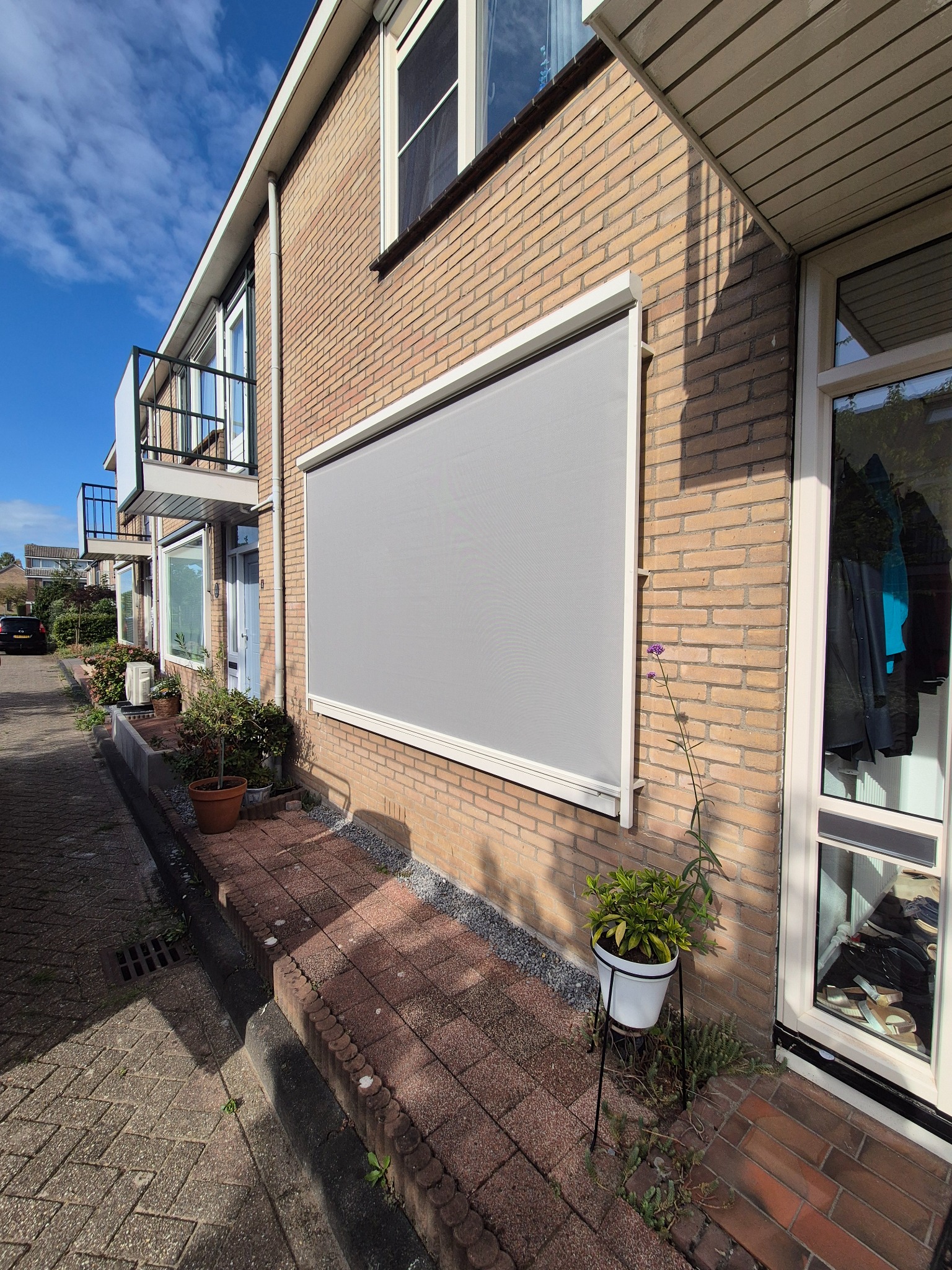 Lichtgrijs screen gemonteerd voor een raam aan de voorgevel
