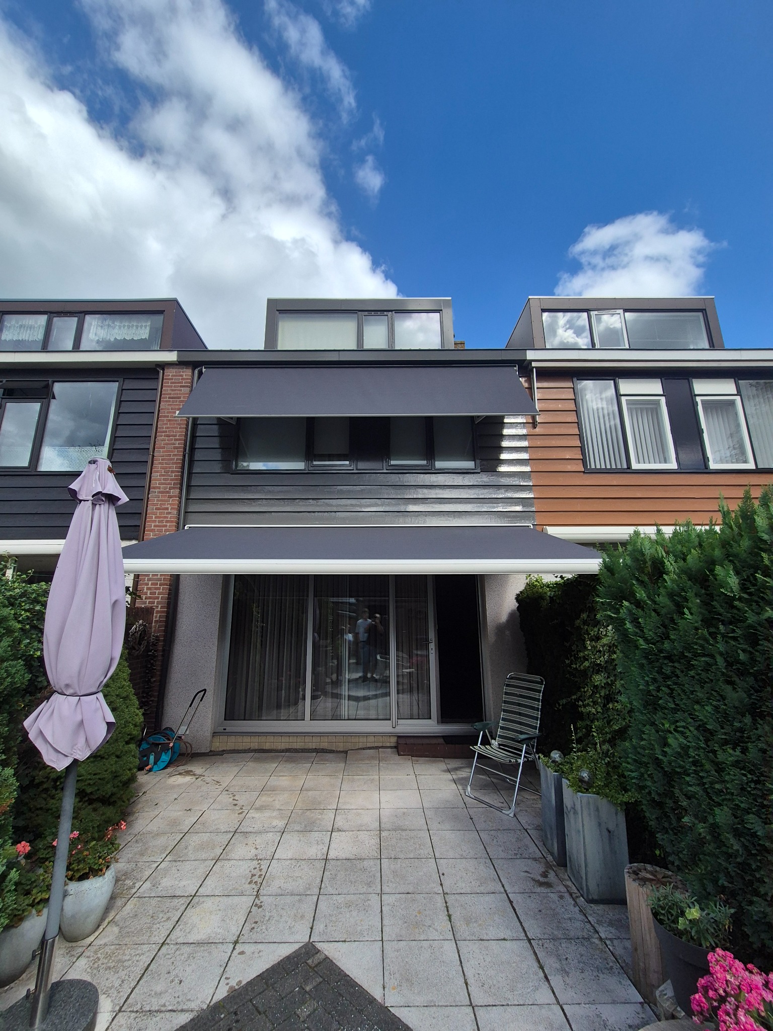 Twee donkergrijze zonneschermen gemonteerd aan een woning